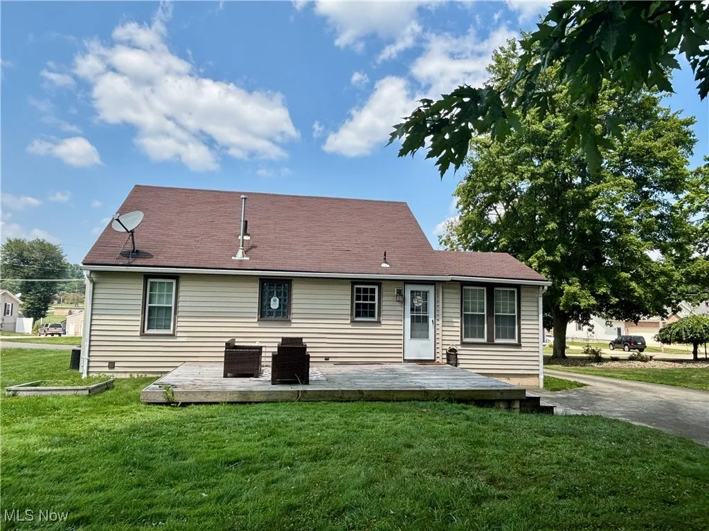 Rear view of house with a lawn and a deck