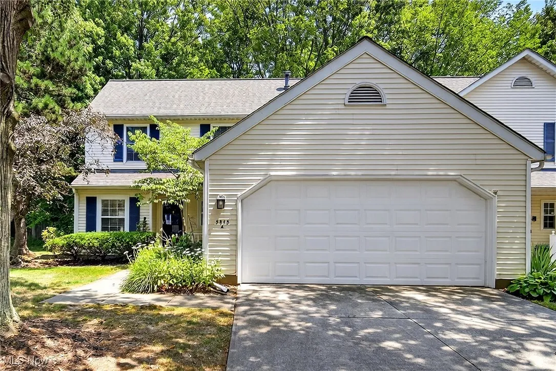 Traditional-style home with an attached garage, driveway, and a shingled roof