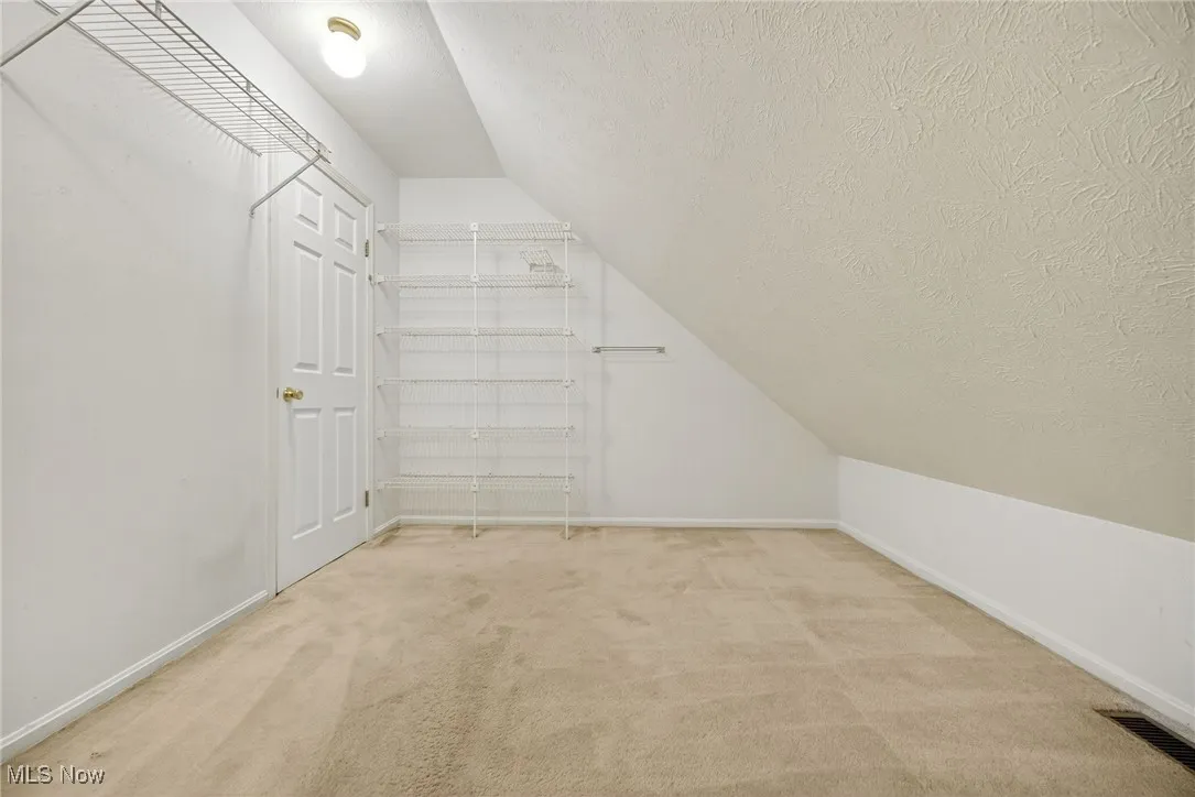 2nd floor bedroom Spacious closet featuring vaulted ceiling and light colored carpet