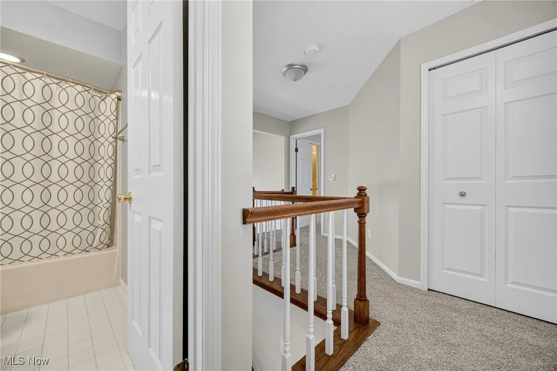 Hall featuring an upstairs landing and carpet flooring