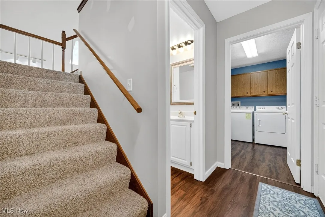 Staircase with washing machine and dryer and wood finished floors