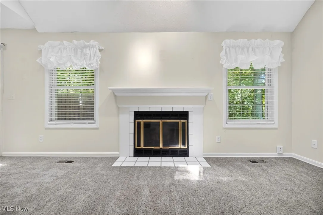 Unfurnished living room with carpet floors and a tiled fireplace