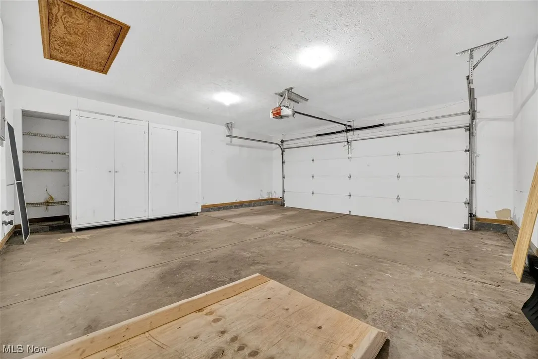 Garage with a garage door opener, built in cabinets, hot and cold hose bibs, pull down steps to garage attic.