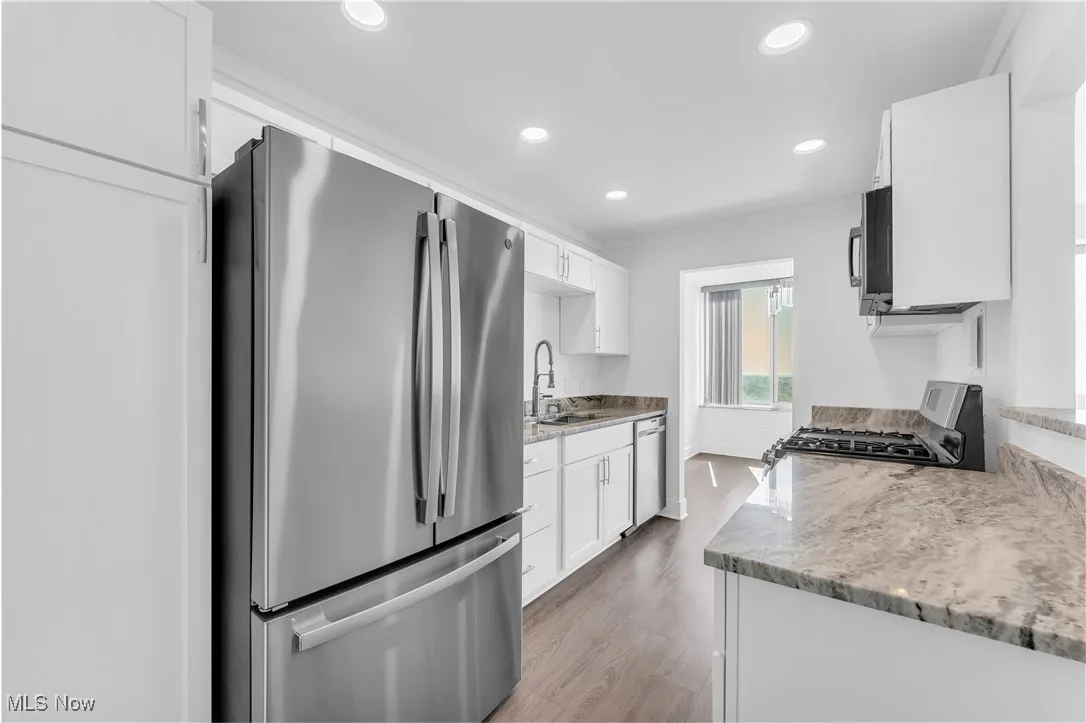 Kitchen featuring appliances with stainless steel finishes, light wood-style floors, recessed lighting, white cabinetry, and ornamental molding