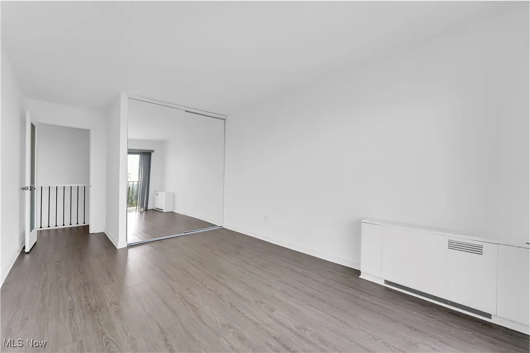 Unfurnished room featuring wood finished floors and radiator heating unit