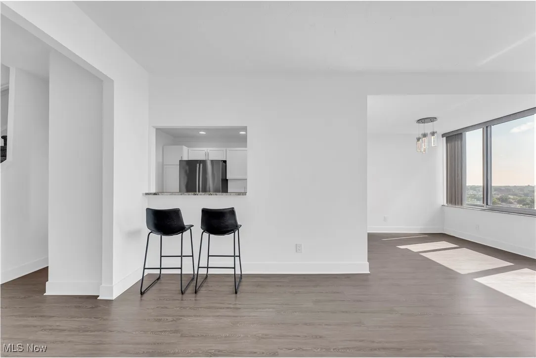 Kitchen with white cabinets, freestanding refrigerator, wood finished floors, a breakfast bar, and recessed lighting