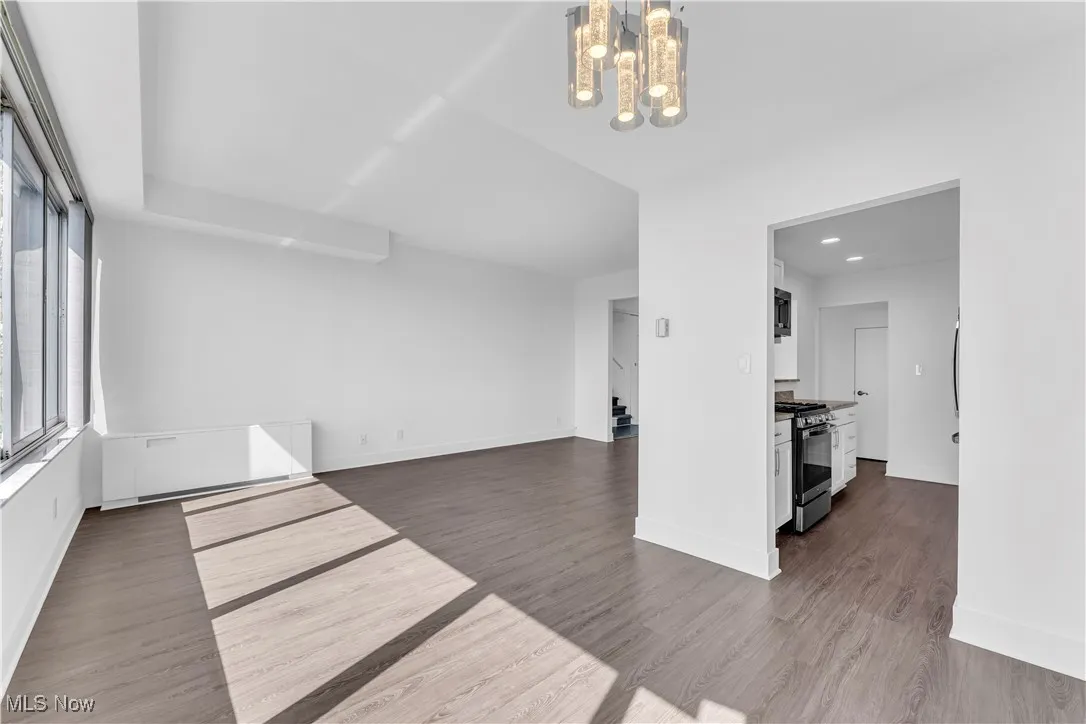 Unfurnished living room with dark wood finished floors, a chandelier, and recessed lighting