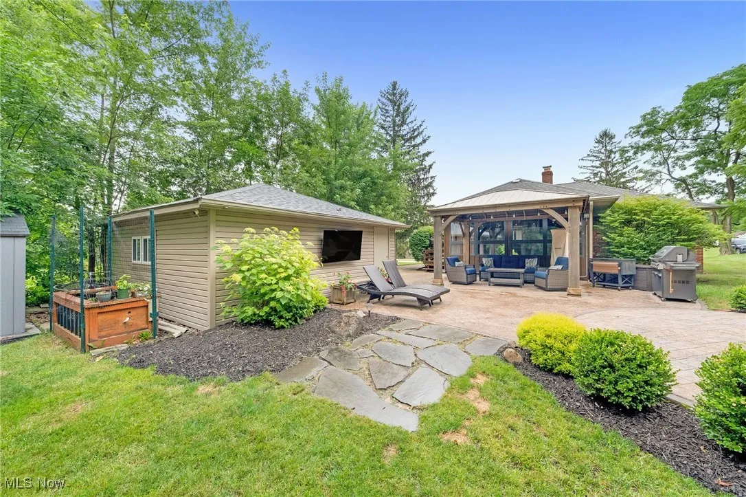 Rear view of house featuring an outdoor living space, a gazebo, a patio area, a chimney, and a yard