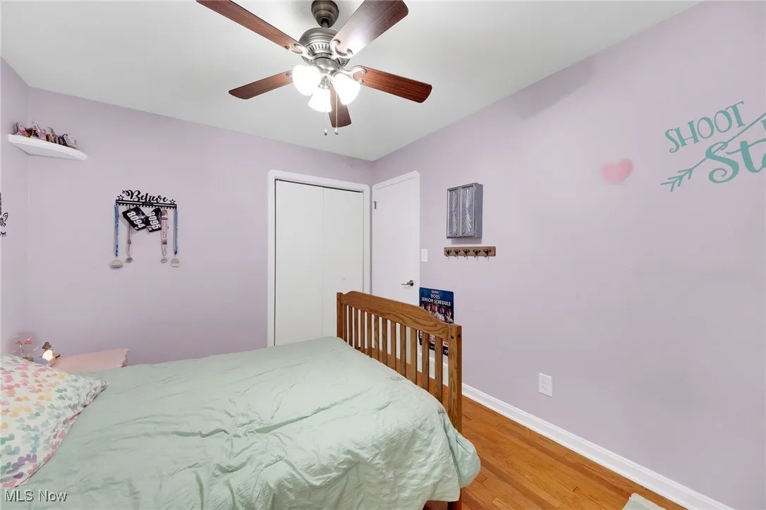 Bedroom with light wood finished floors, ceiling fan, and a closet