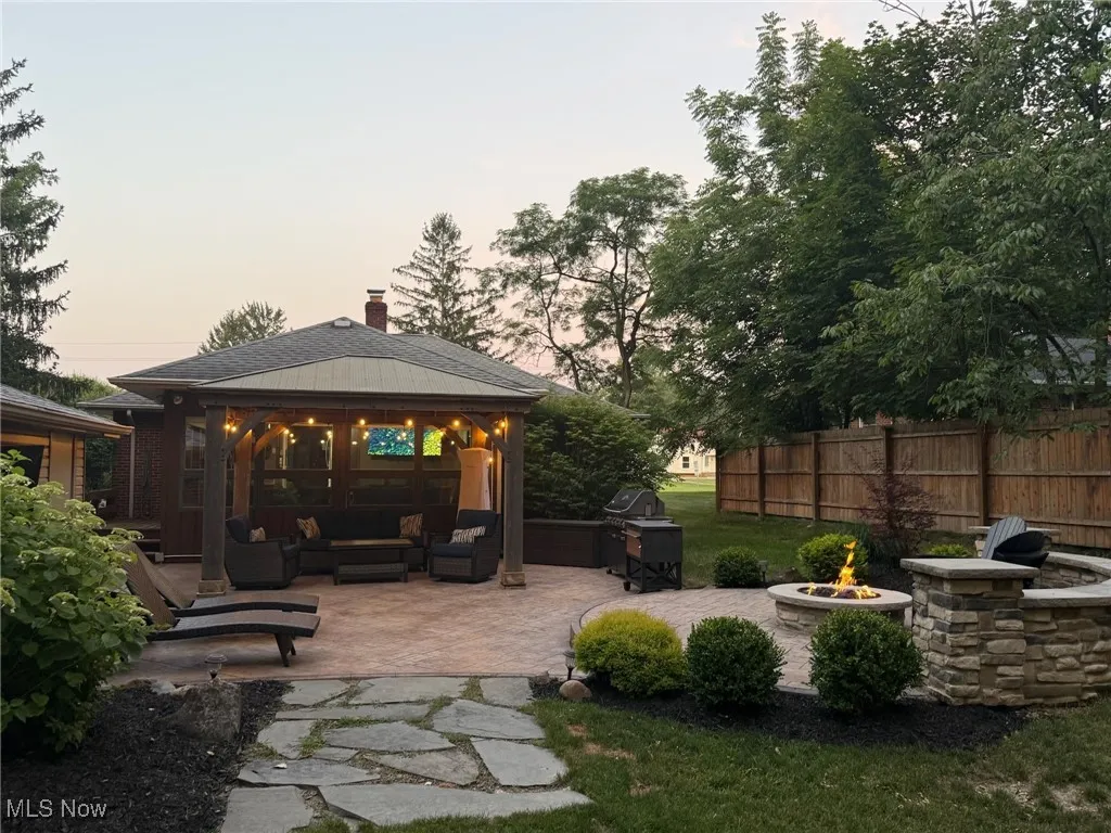 Yard at dusk with an outdoor living space with a fire pit, a gazebo, and a patio area