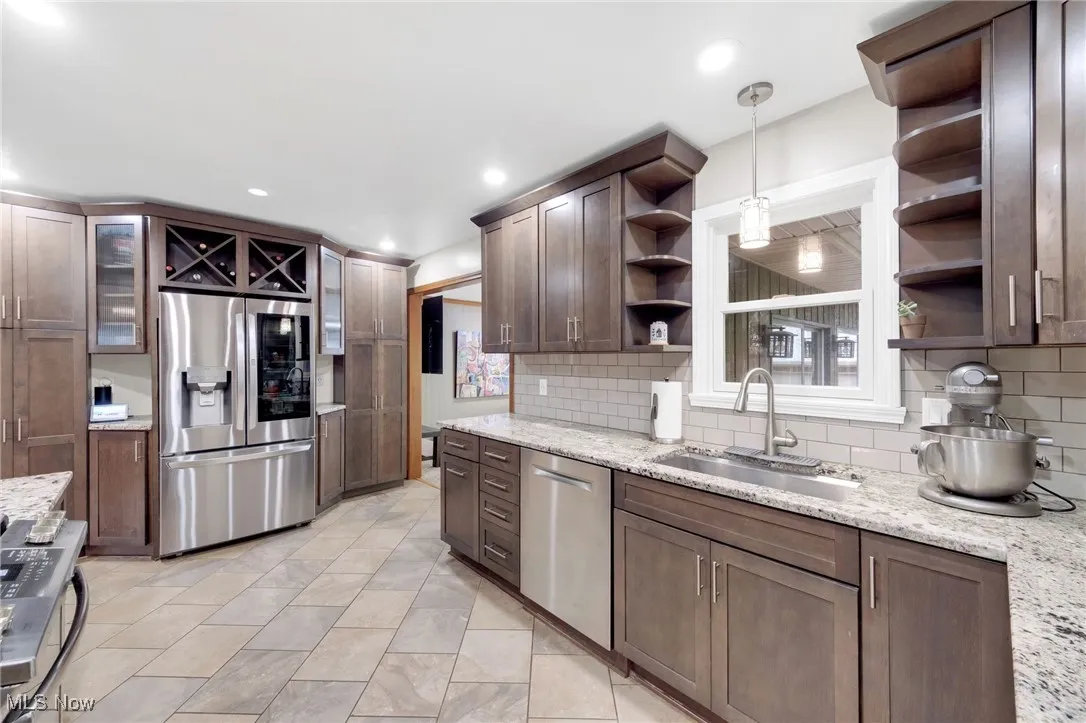 Kitchen featuring open shelves, appliances with stainless steel finishes, tasteful backsplash, light stone countertops, and recessed lighting