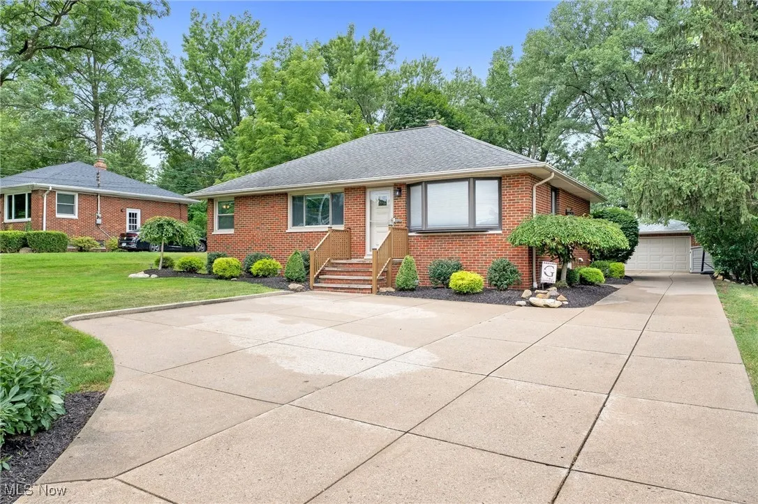 View of front of property featuring brick siding, a front lawn, a shingled roof, and an outdoor structure