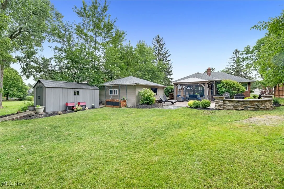 View of grassy yard featuring a gazebo, an outdoor structure, and a patio