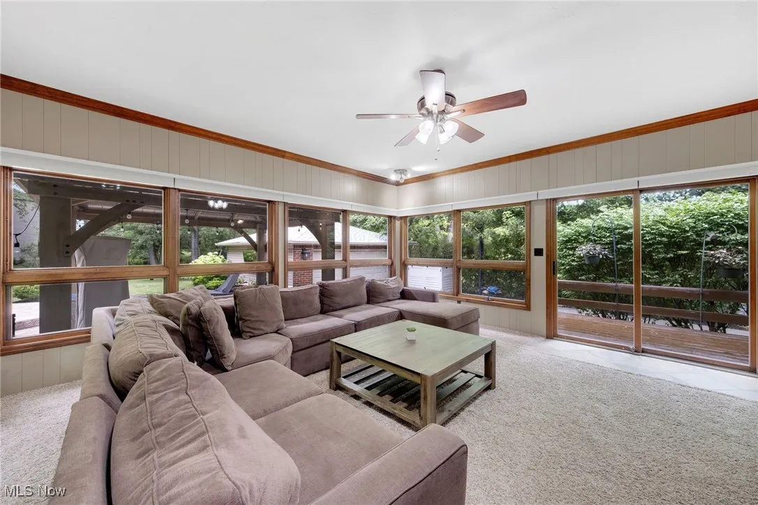 Living room with ceiling fan, carpet flooring, and ornamental molding