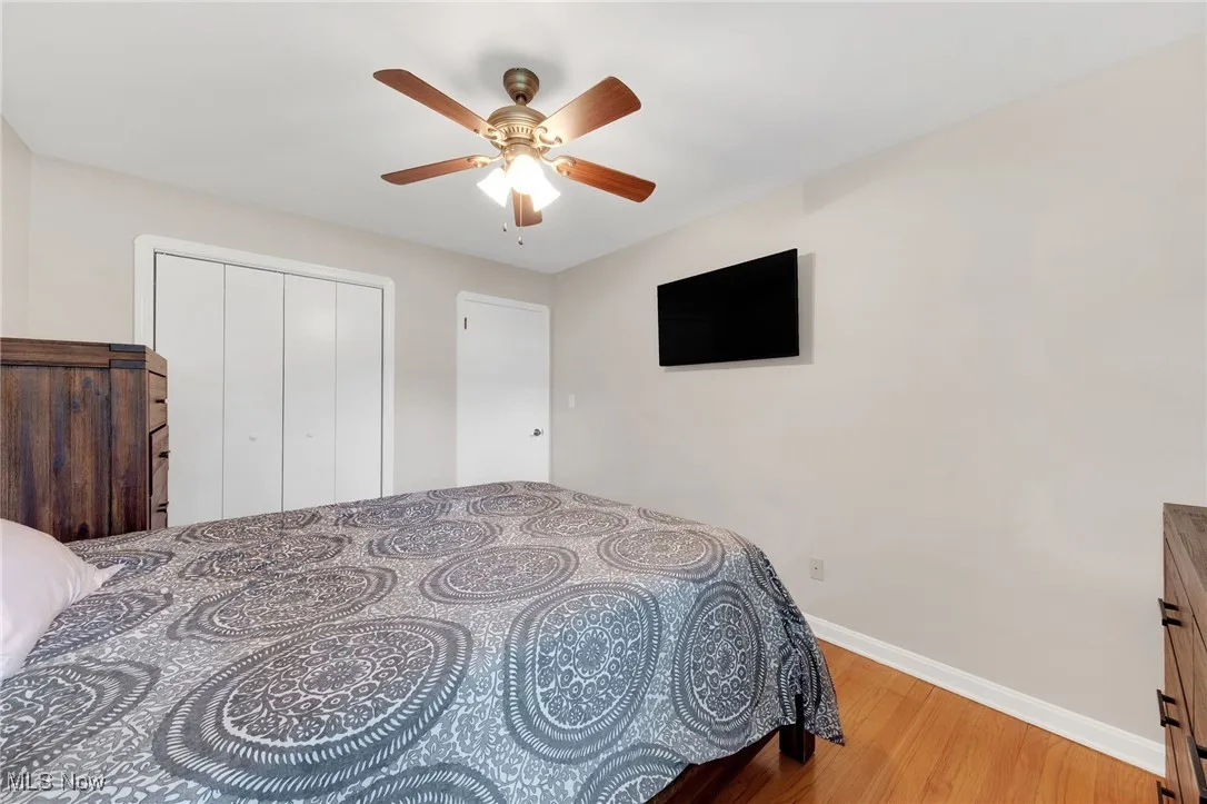 Bedroom with wood finished floors, ceiling fan, and a closet