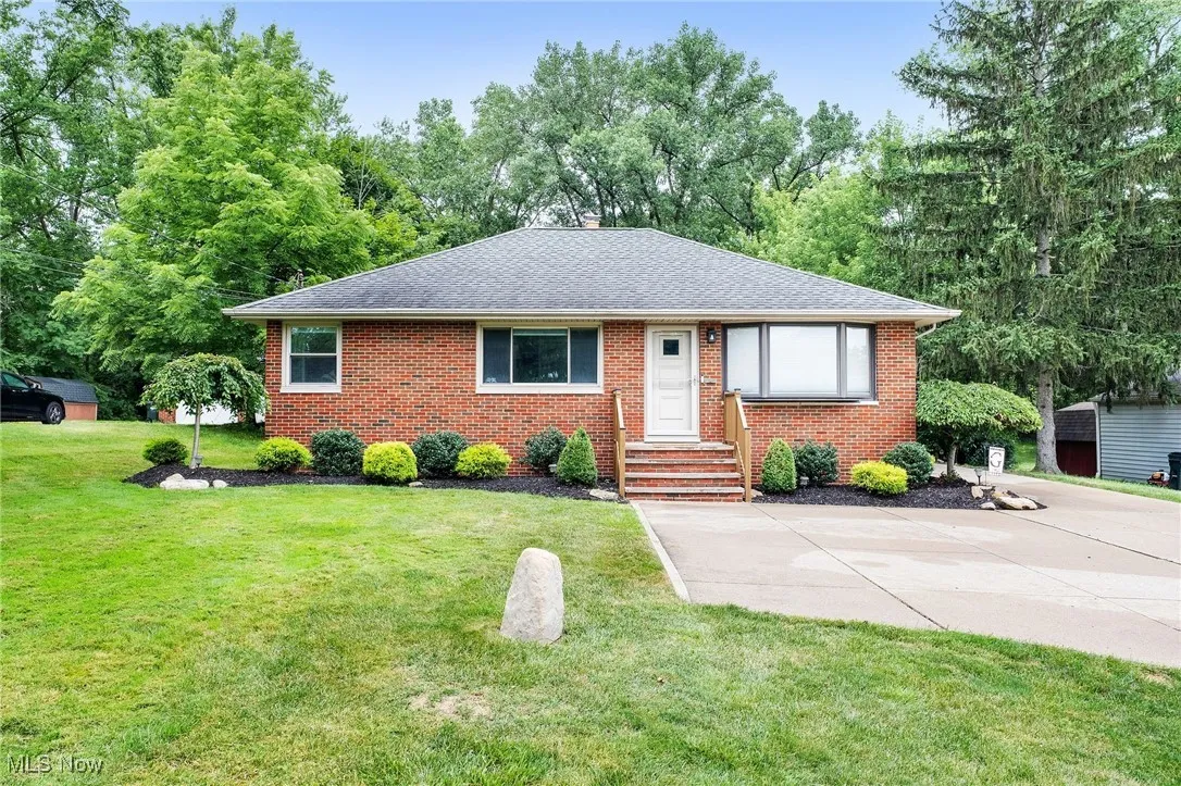 View of front facade with roof with shingles, brick siding, and a front lawn