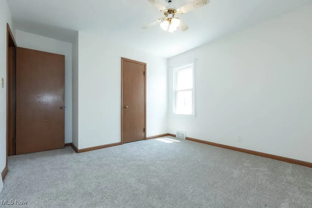Unfurnished bedroom with light carpet and a ceiling fan