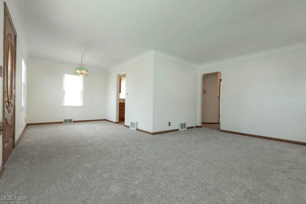 Unfurnished room with arched walkways and carpet