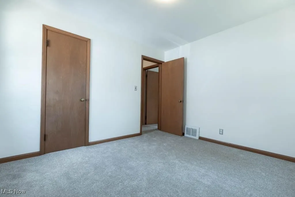 Unfurnished bedroom with light carpet and baseboards