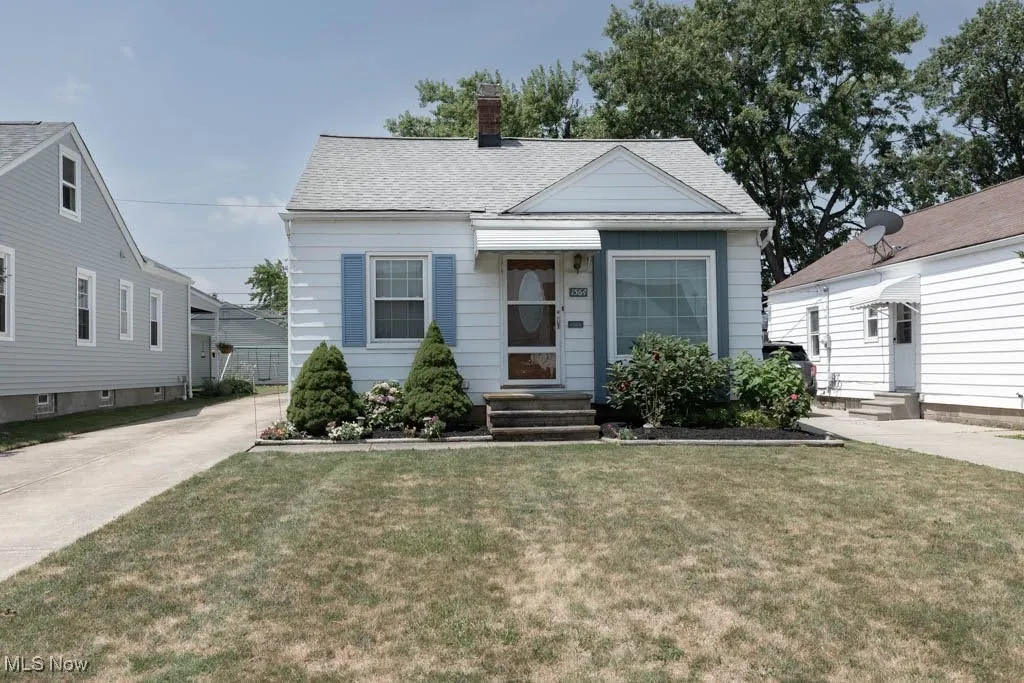 View of front of property featuring entry steps, a chimney, a front lawn, and a shingled roof