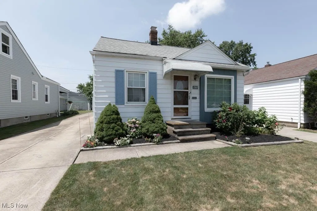 View of front of property with a chimney, a front lawn, and concrete driveway