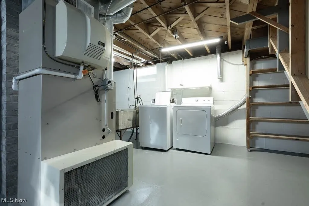 Below grade area with washer and clothes dryer, heating unit, and concrete block wall