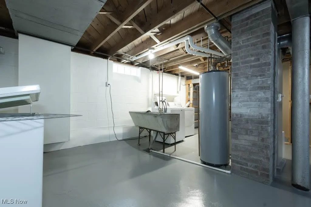 Basement featuring separate washer and dryer, gas water heater, and concrete block wall