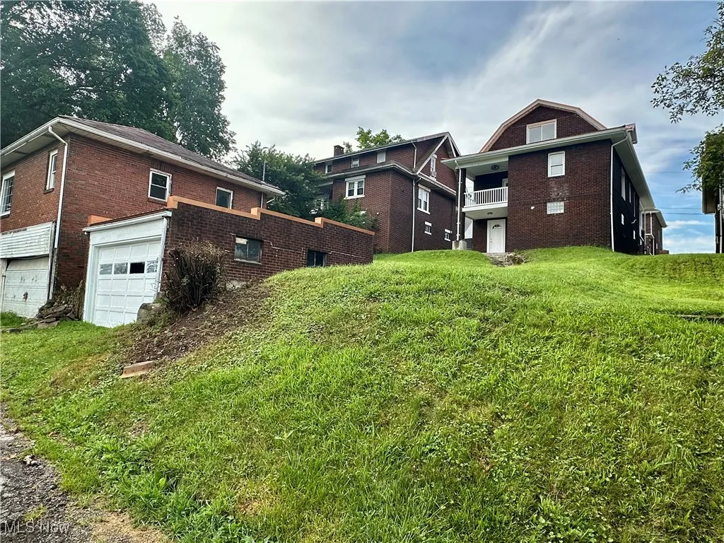 Back view of home with a garage and yard