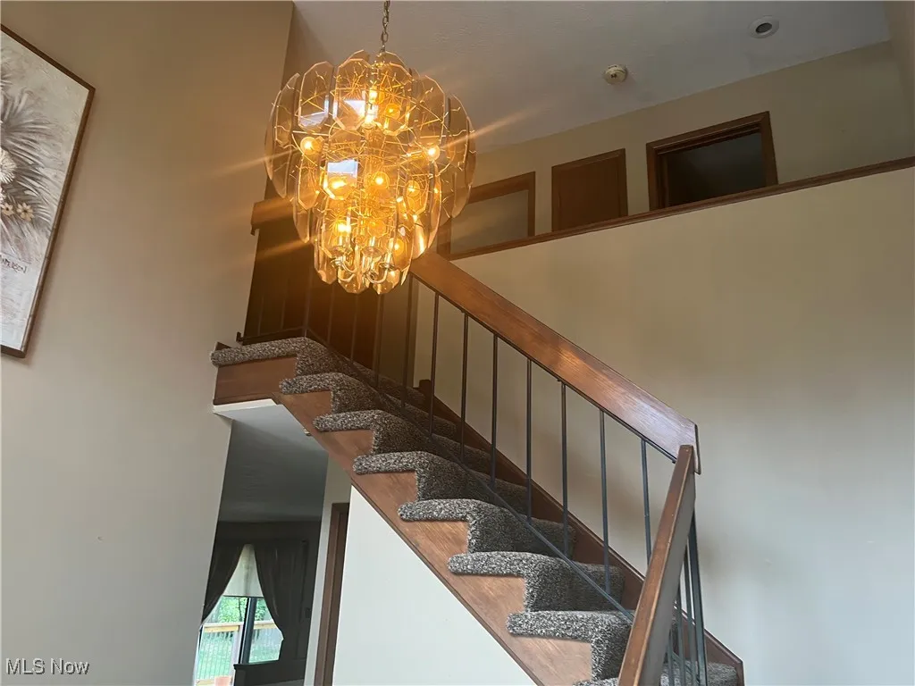 Staircase featuring a chandelier
