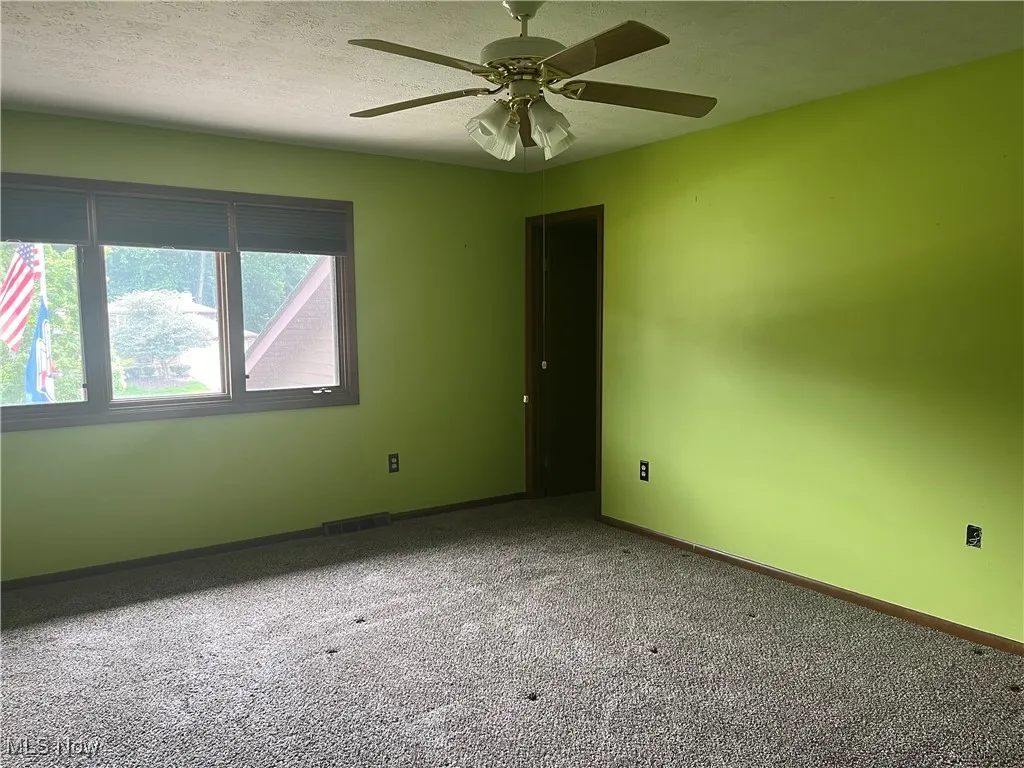 Carpeted Primary Bedroom has a ceiling fan and door to walk thru closets
