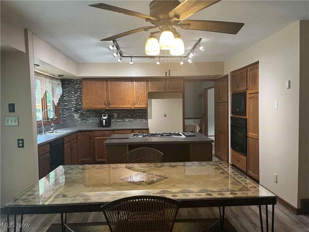Features a kitchen island, wood finished floors, a ceiling fan and rail lighting.  The kitchen table stays.