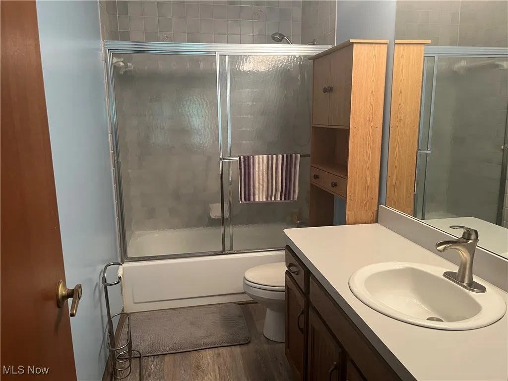 Second Full bathroom upstairs features vanity, shower / bath combination with glass door, and wood finished floors