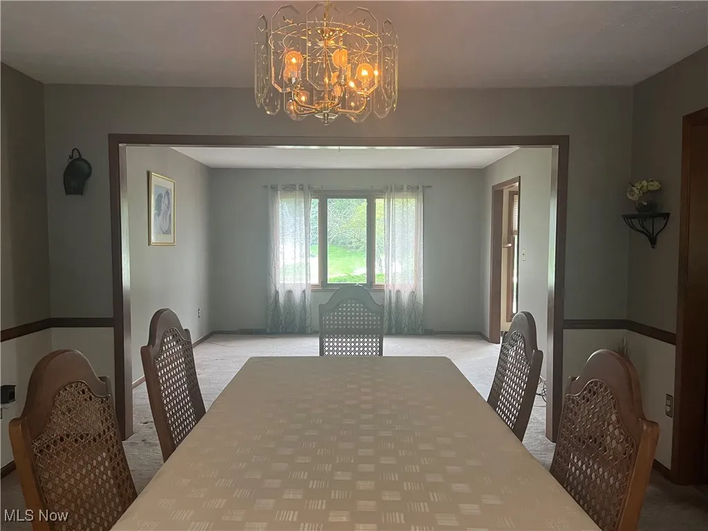 Dining Room with a chandelier and light colored carpet leads to the Living Room.