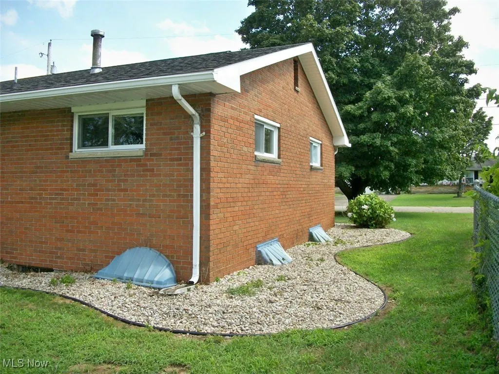 View of property exterior with a yard and brick siding
