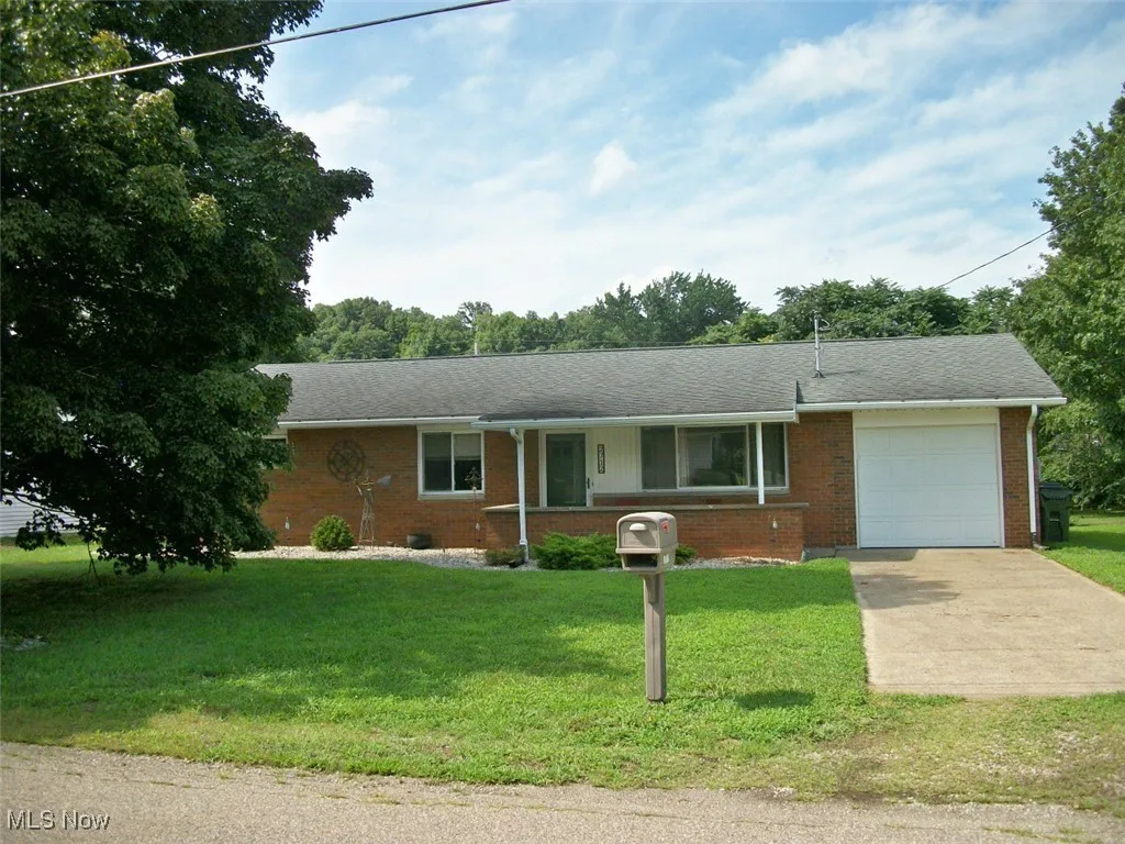 Single story home featuring an attached garage, concrete driveway, brick siding, and a front yard
