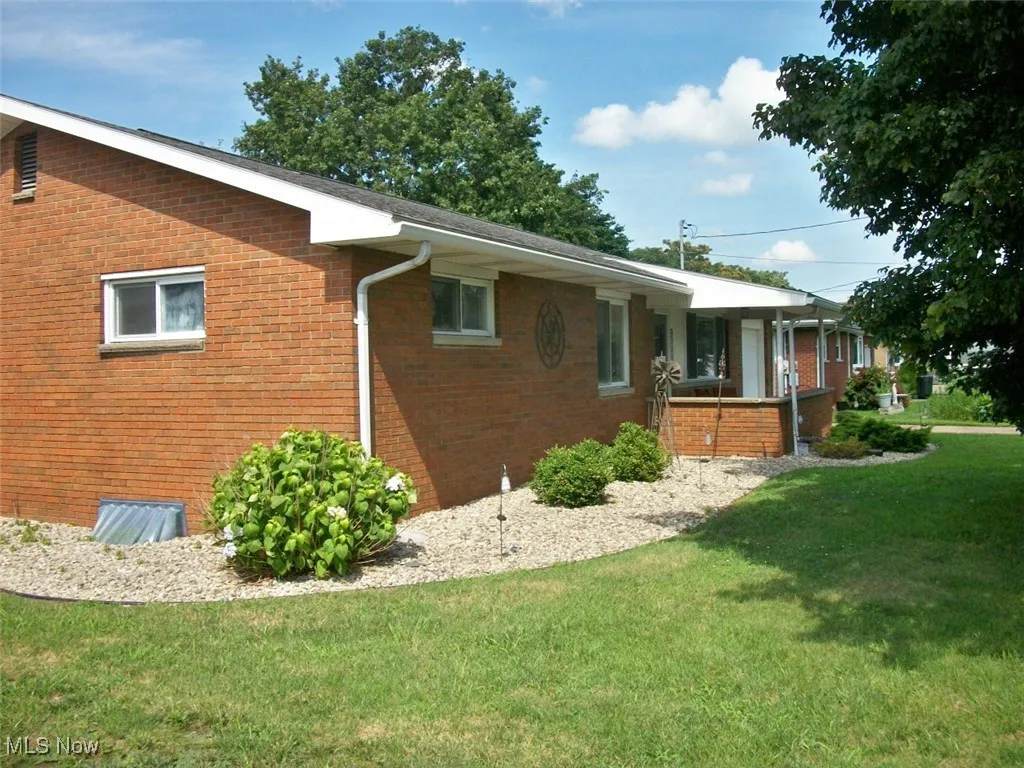 View of property exterior featuring brick siding and a lawn