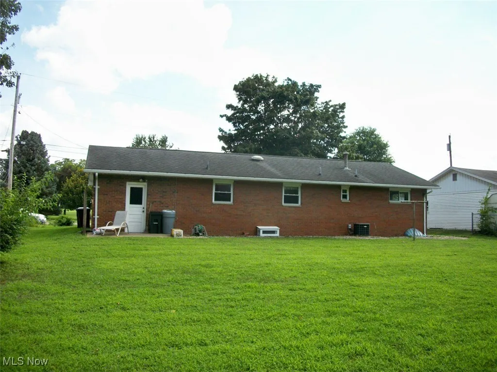 Rear view of property featuring brick siding and a lawn