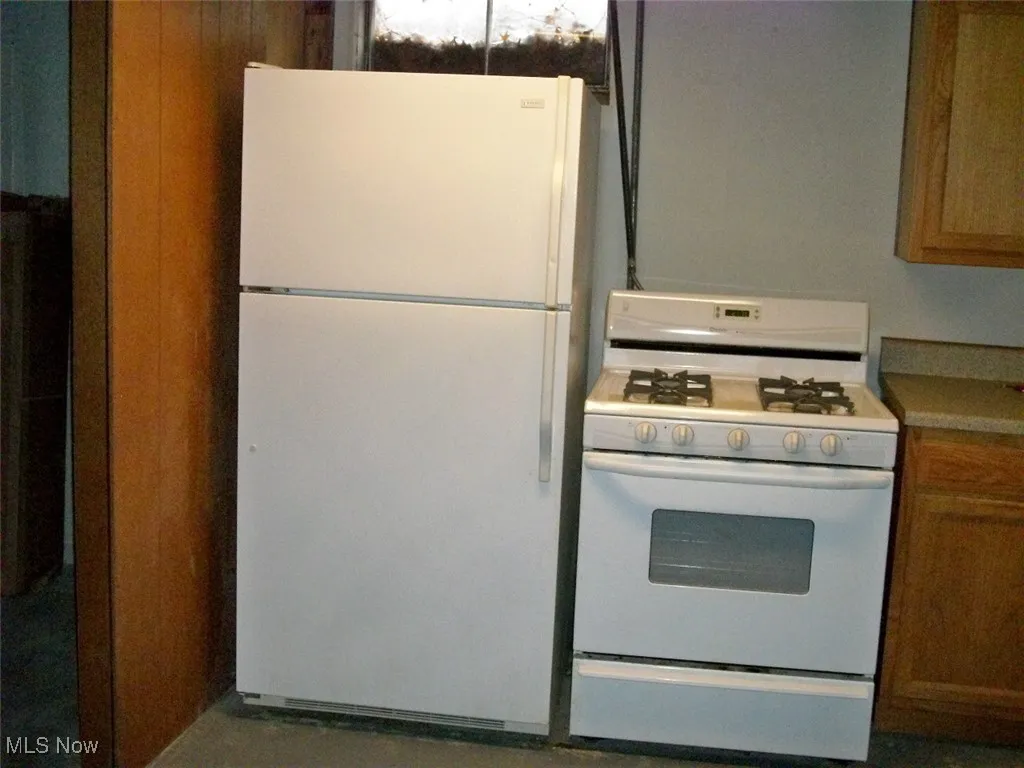 Summer downstairs Kitchen featuring white appliances, brown cabinetry, and light countertops