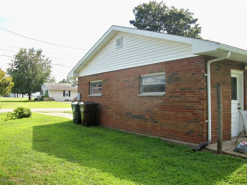 View of side of property featuring a yard and brick siding