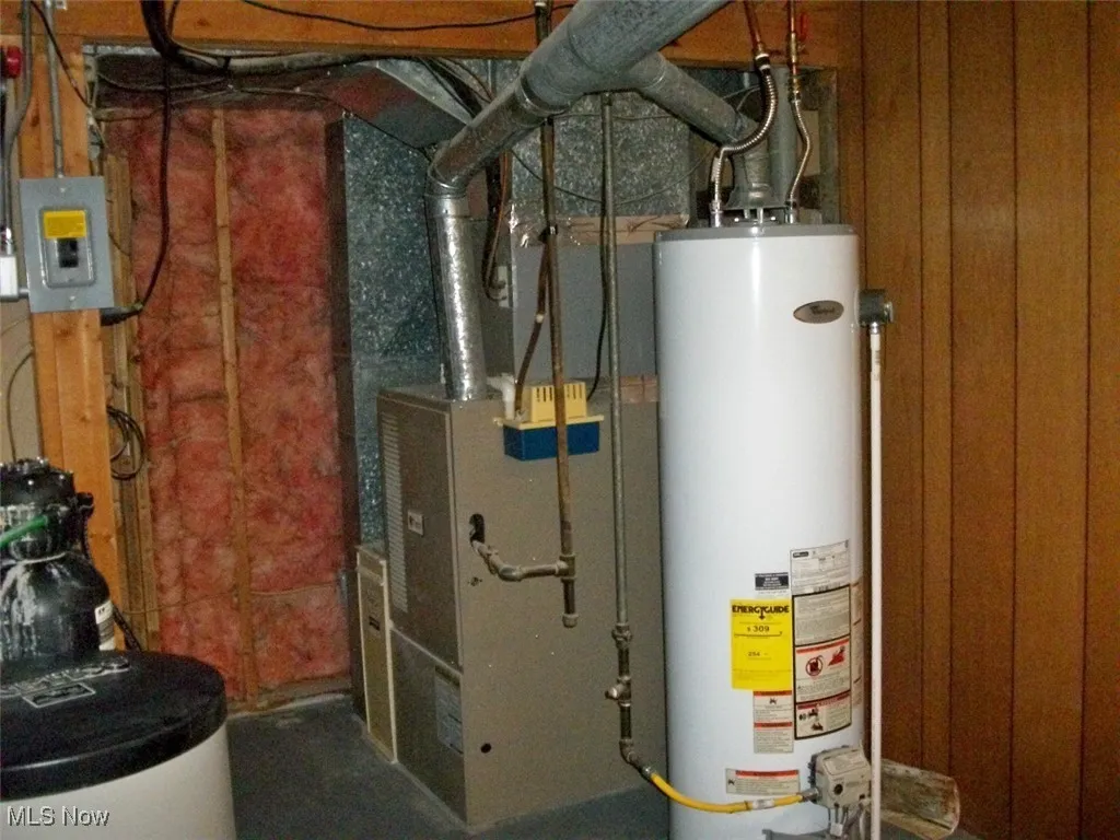 Utility room featuring water heater, heating unit, with whole house filtration system.