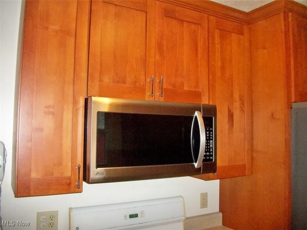 Detailed view of stainless steel microwave and brown cabinetry
