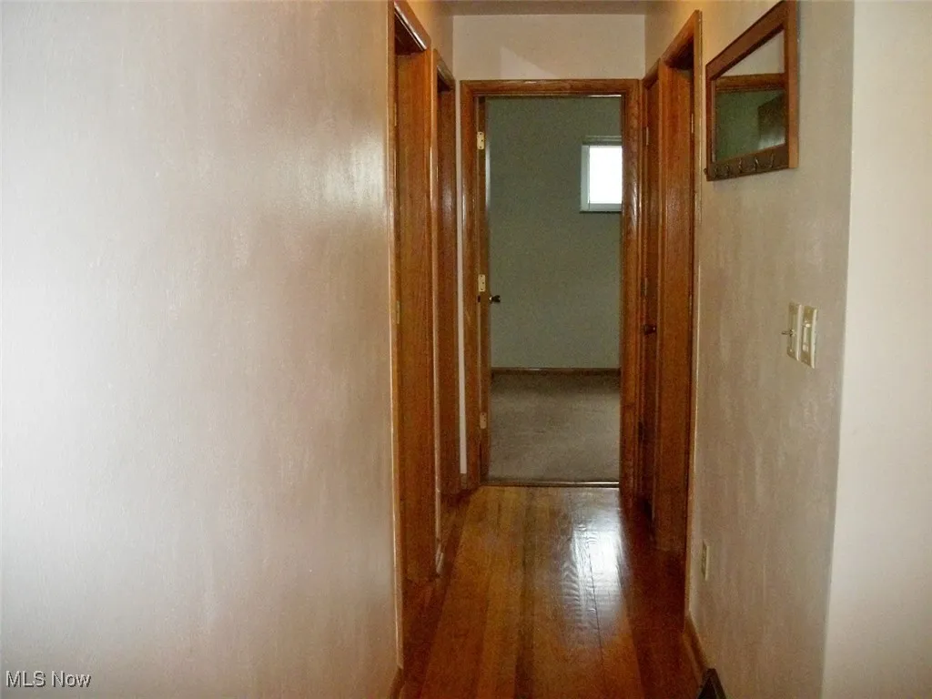 Hall featuring wood finished floors & attic fan in ceiling.