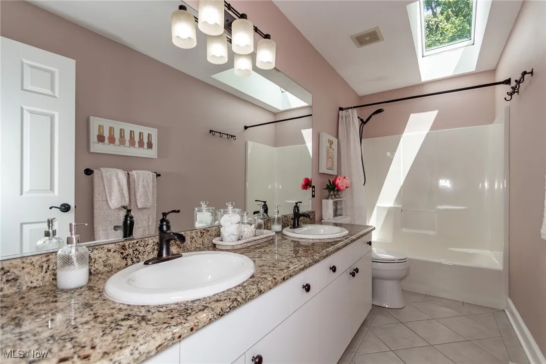 2nd floor full Bathroom featuring a skylight, double vanity, ceramic tile floors, and shower/tub combo