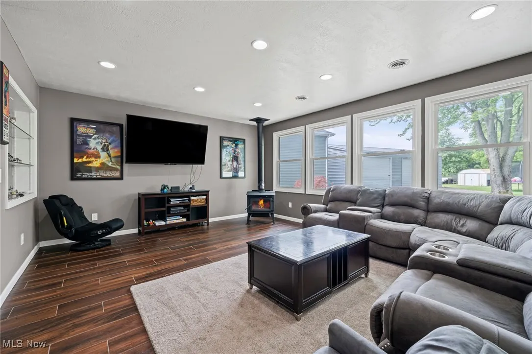 Family room featuring a wood stove, wood finished floors, recessed lighting, and healthy amount of natural light