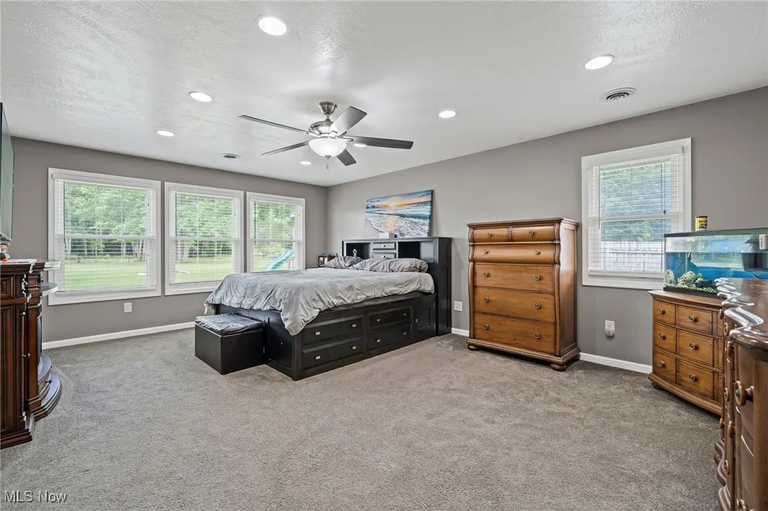Carpeted master bedroom featuring recessed lighting and a ceiling fan