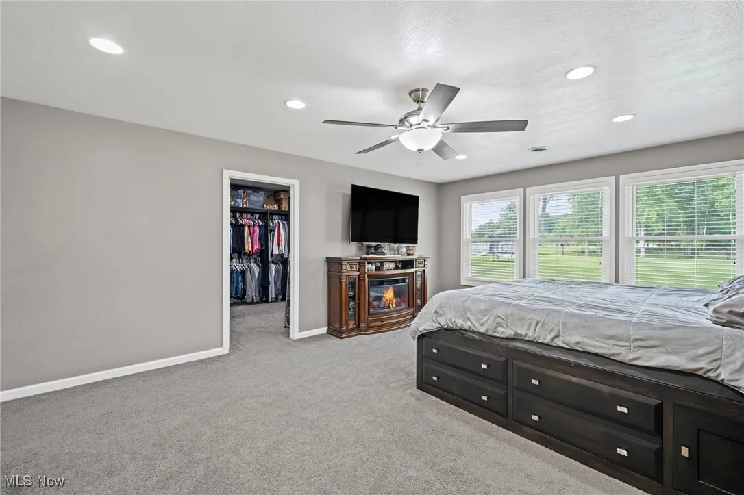 Master Bedroom featuring light carpet, recessed lighting, a spacious closet, and a ceiling fan