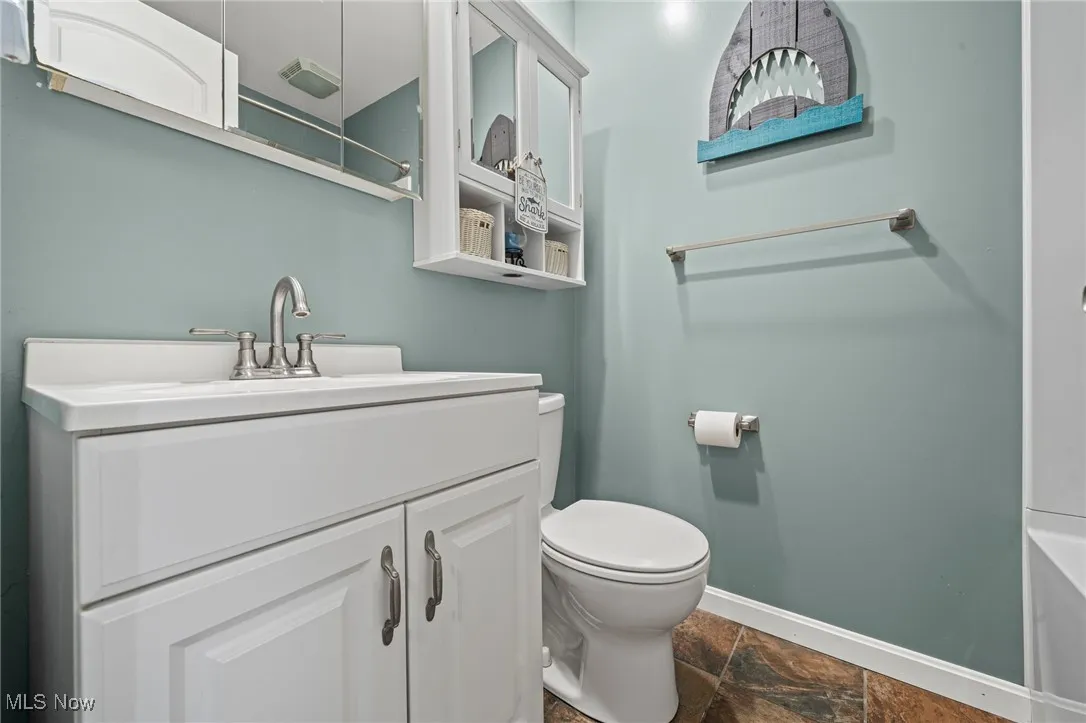 Full bath featuring stone finish floors and vanity