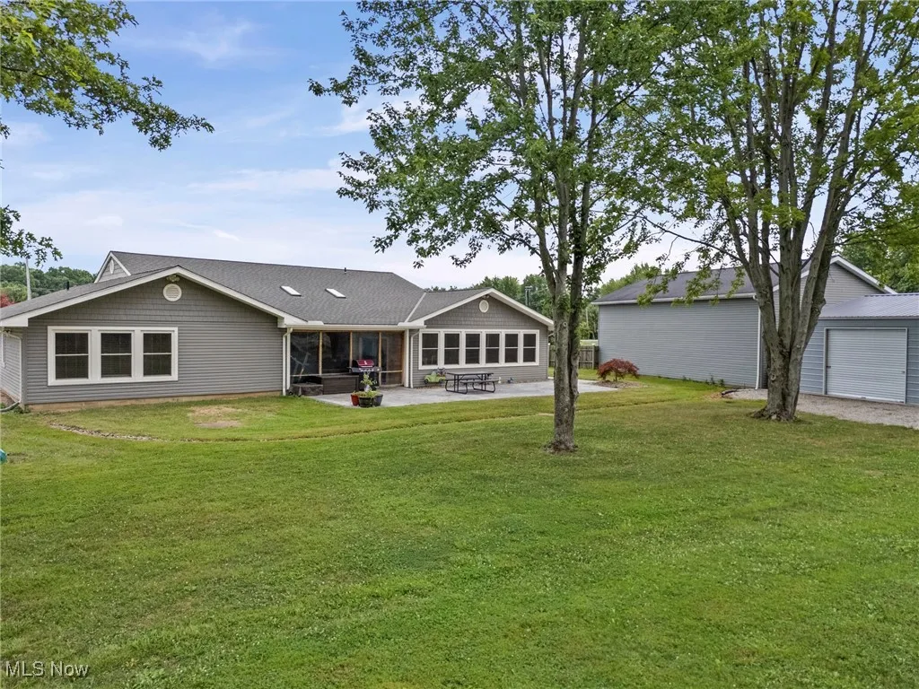 Rear view of house featuring a patio, a yard, and a detached garage