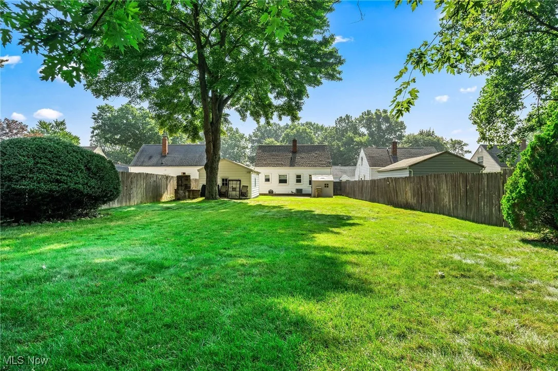View of large fenced backyard facing the house and garage