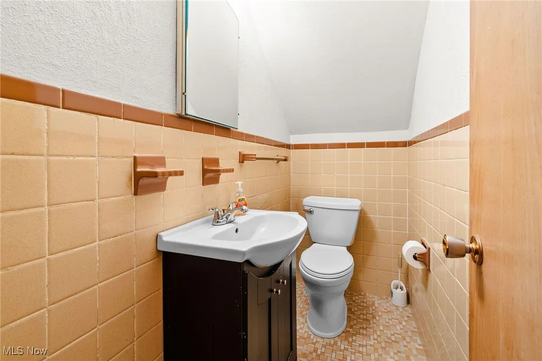 2nd floor Primary Half Bath featuring a newer vanity and original tile walls and floors in outstanding condition